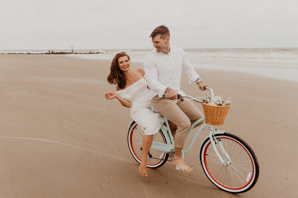 Couple riding a bike on the beach for their engagement 