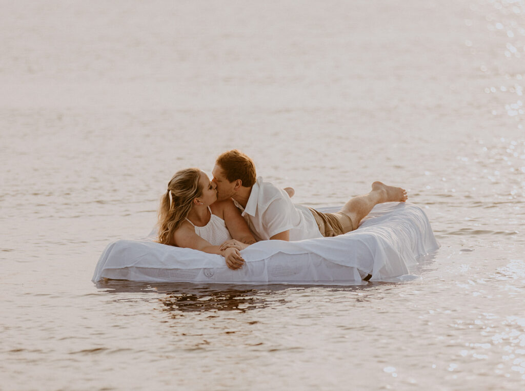 Couple floating in the water on an air mattress for their engagement