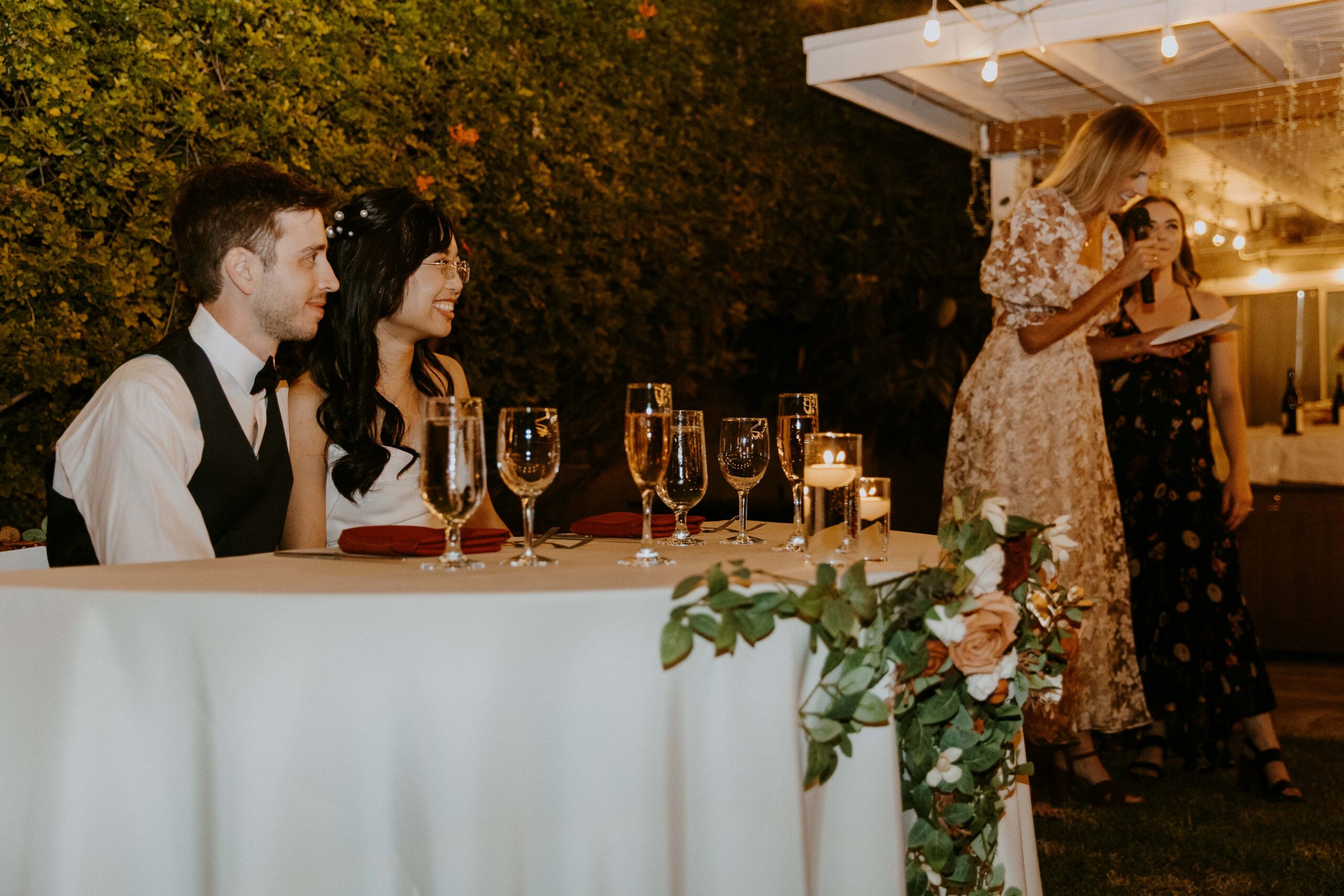An outdoor wedding gathering with the couple sitting at their head table