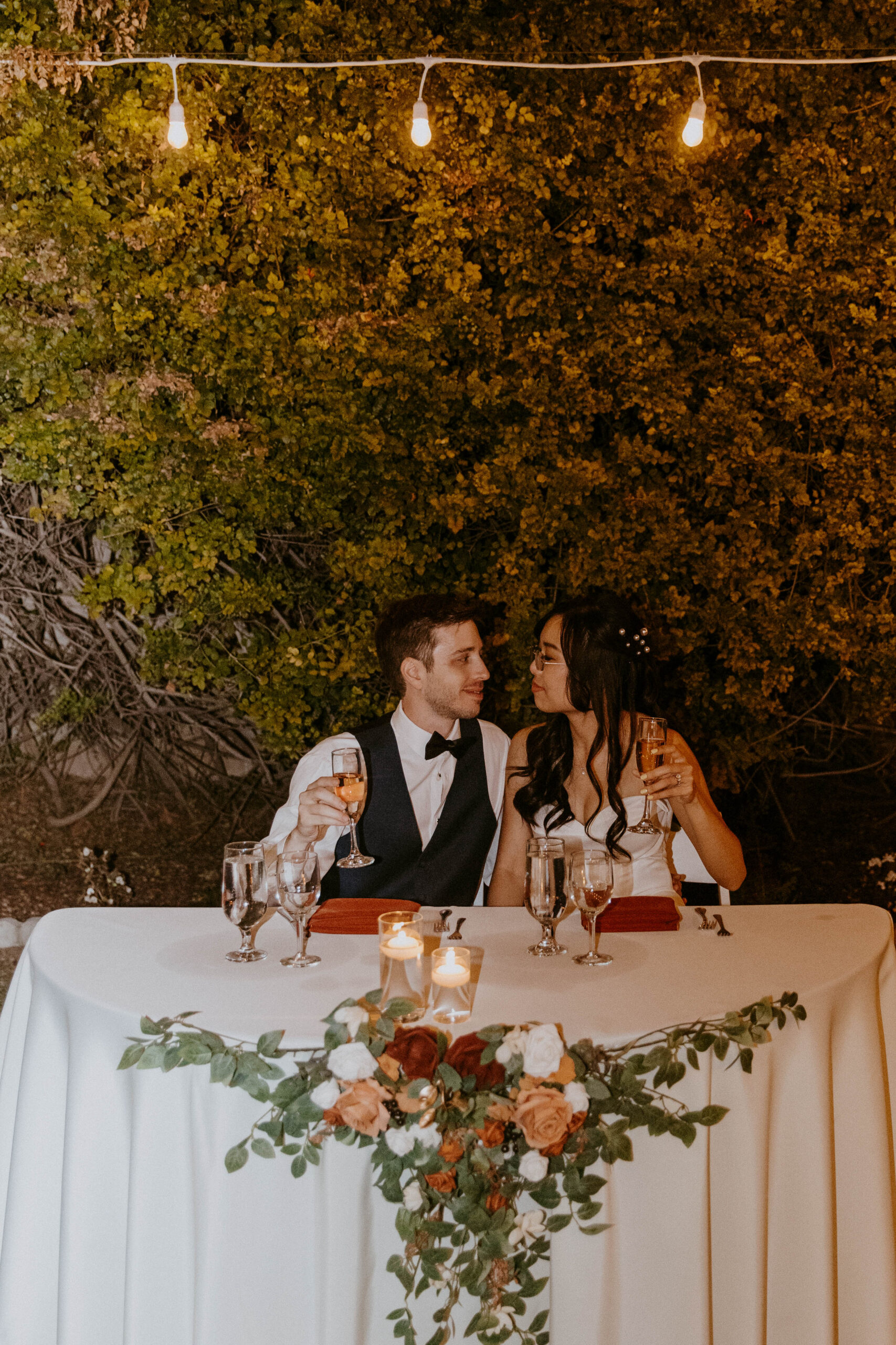 An outdoor wedding gathering with the couple sitting at their head table