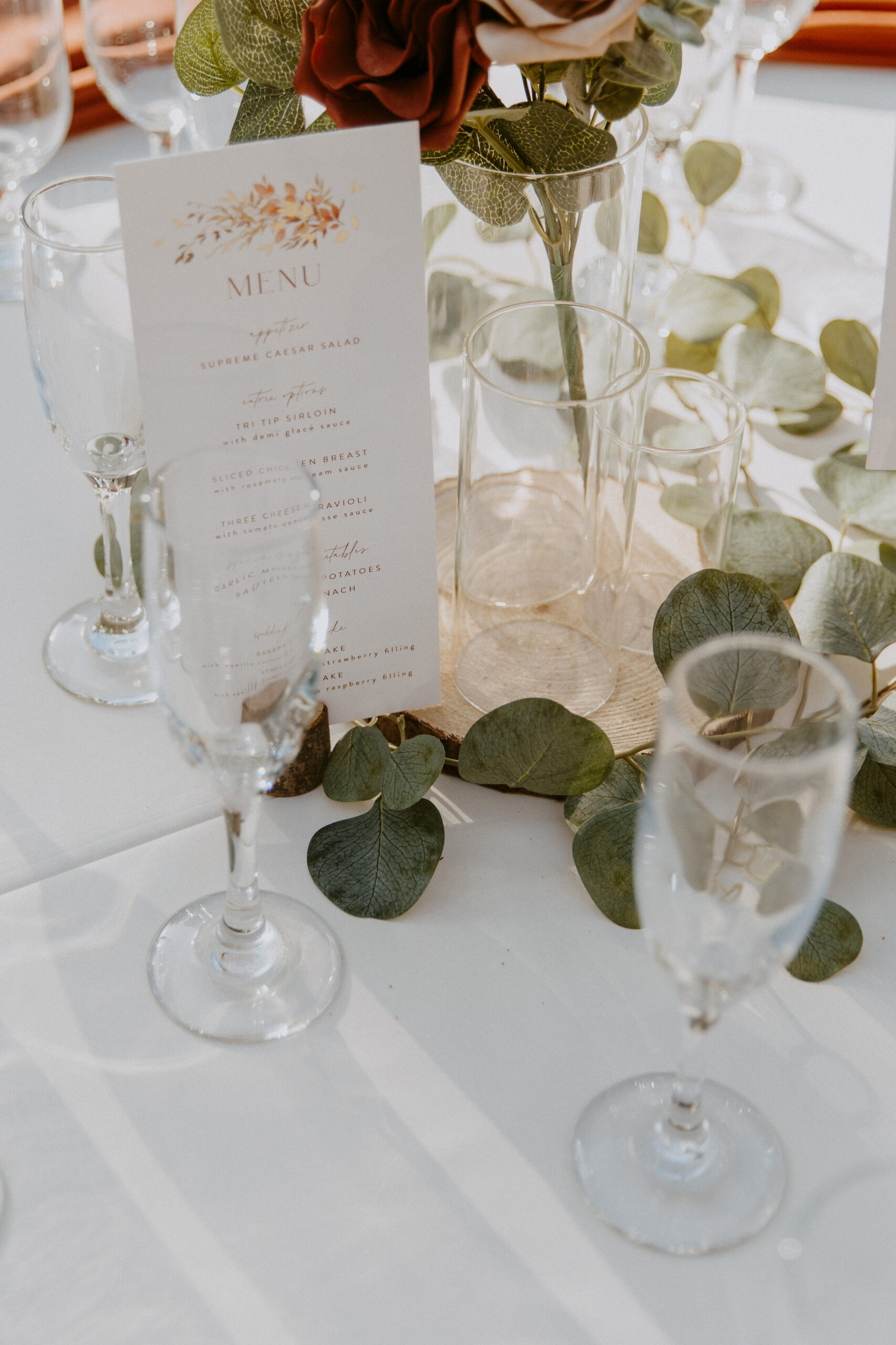 Elegant table setting with a menu card surrounded by greenery and glassware