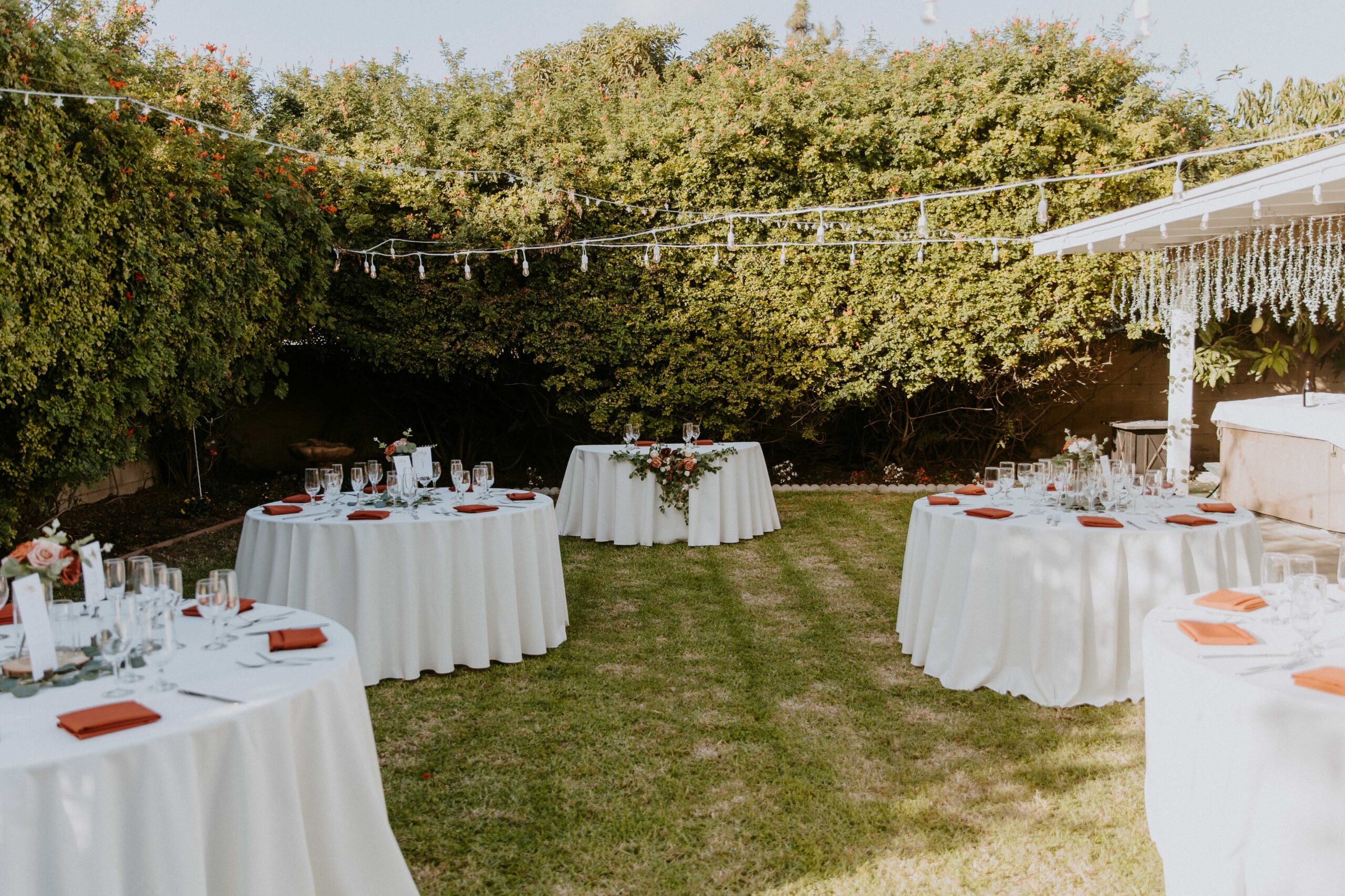 Elegantly set dining table for two with floral centerpiece and candlelight outdoors at an intimate backyard wedding