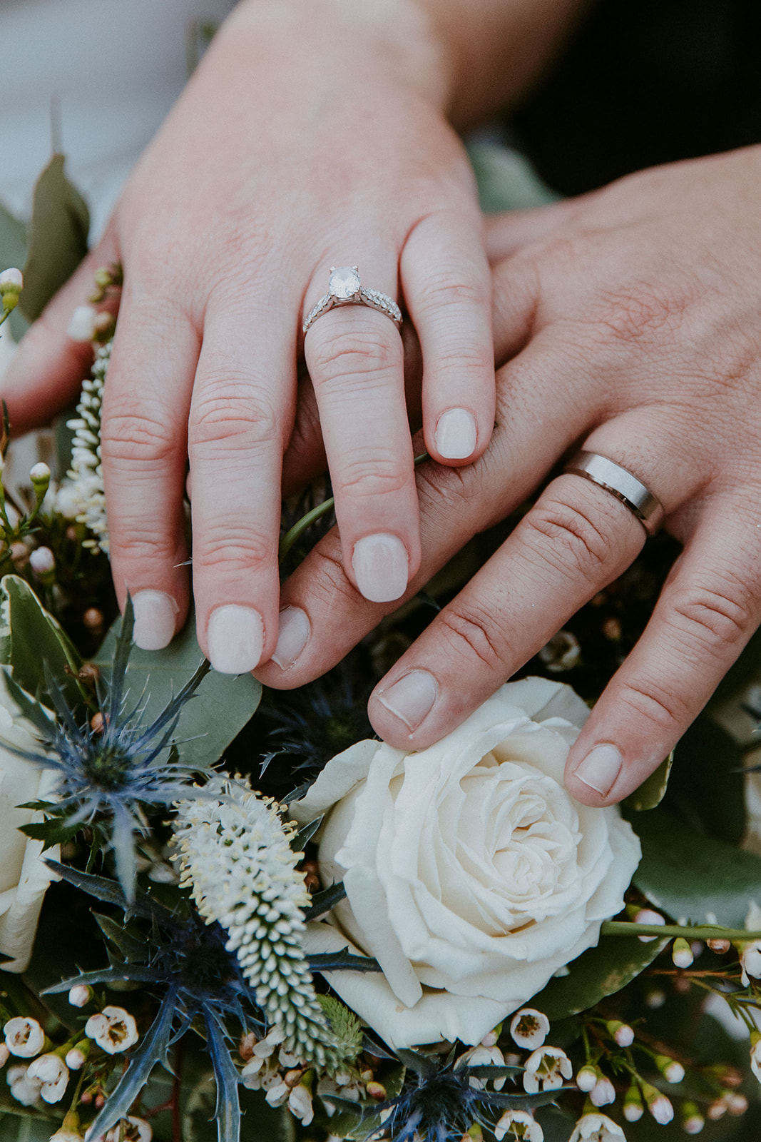 A bride and groom embrace outside a building with large windows. The bride's veil is flowing, and they both have their eyes closed. Trees and foliage are in the background at The Venues at Ogeechee Tech
