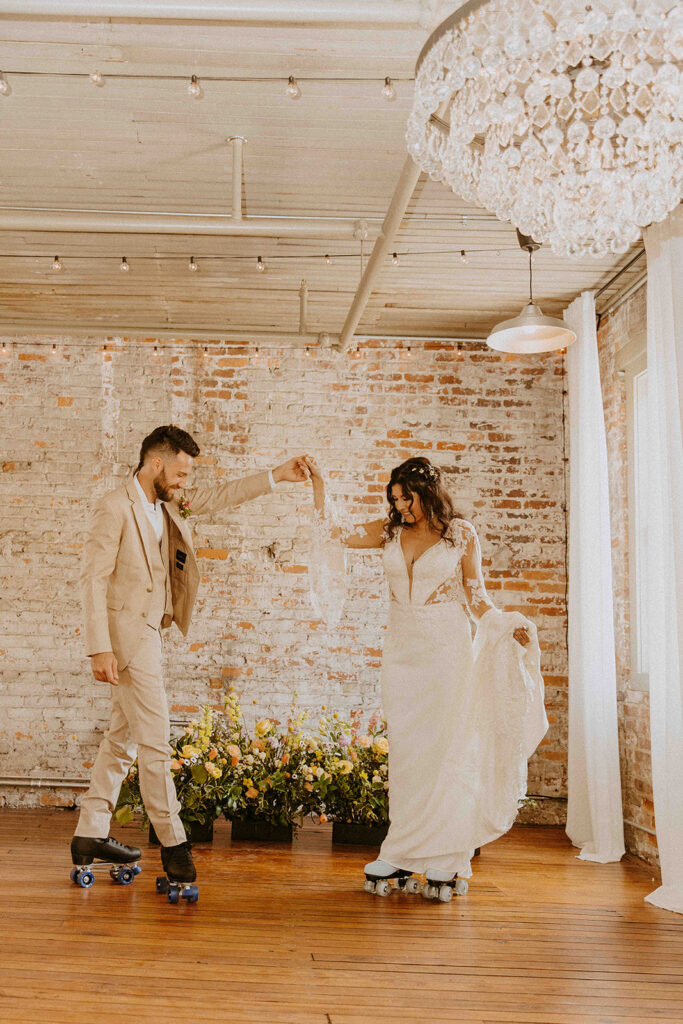 A bride in a white gown and a groom in a dark suit hold hands and dance outdoors on a grassy path, surrounded by autumnal trees. -must have wedding poses