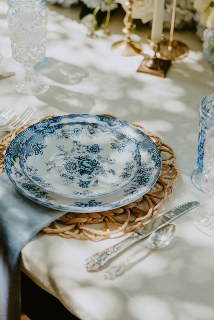 A table decorated with light blue and white flowers, crystal glassware, and two blue taper candles at Wildflower 301