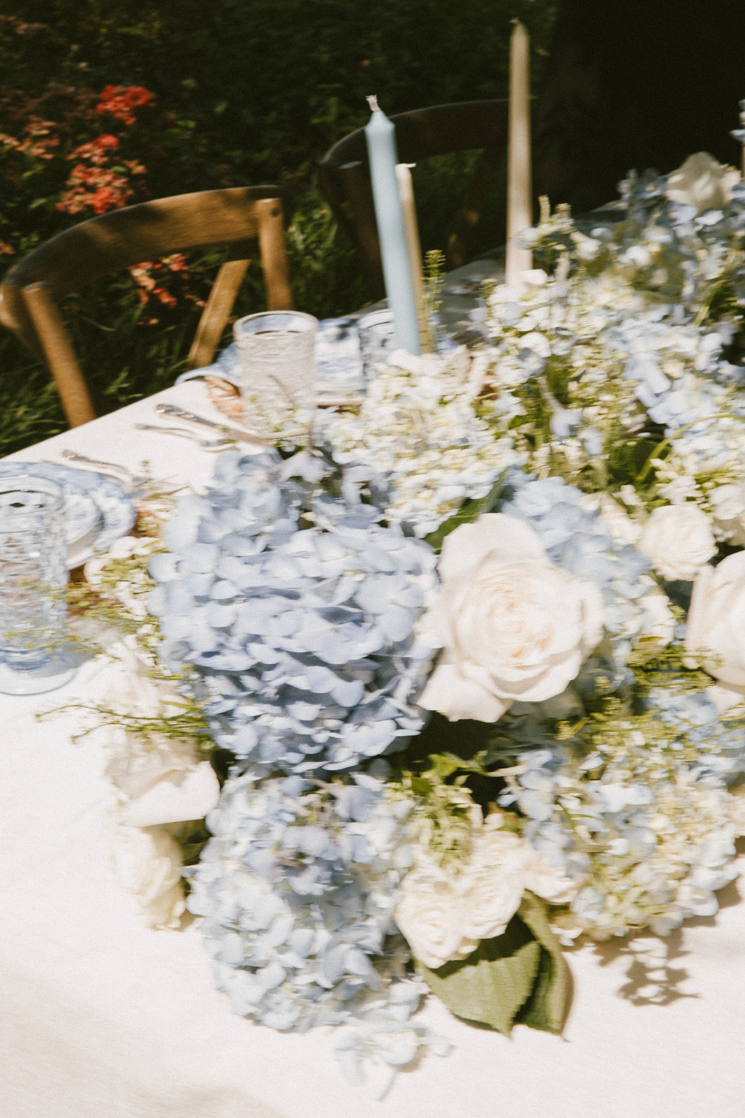 A table decorated with light blue and white flowers, crystal glassware, and two blue taper candles at Wildflower 301