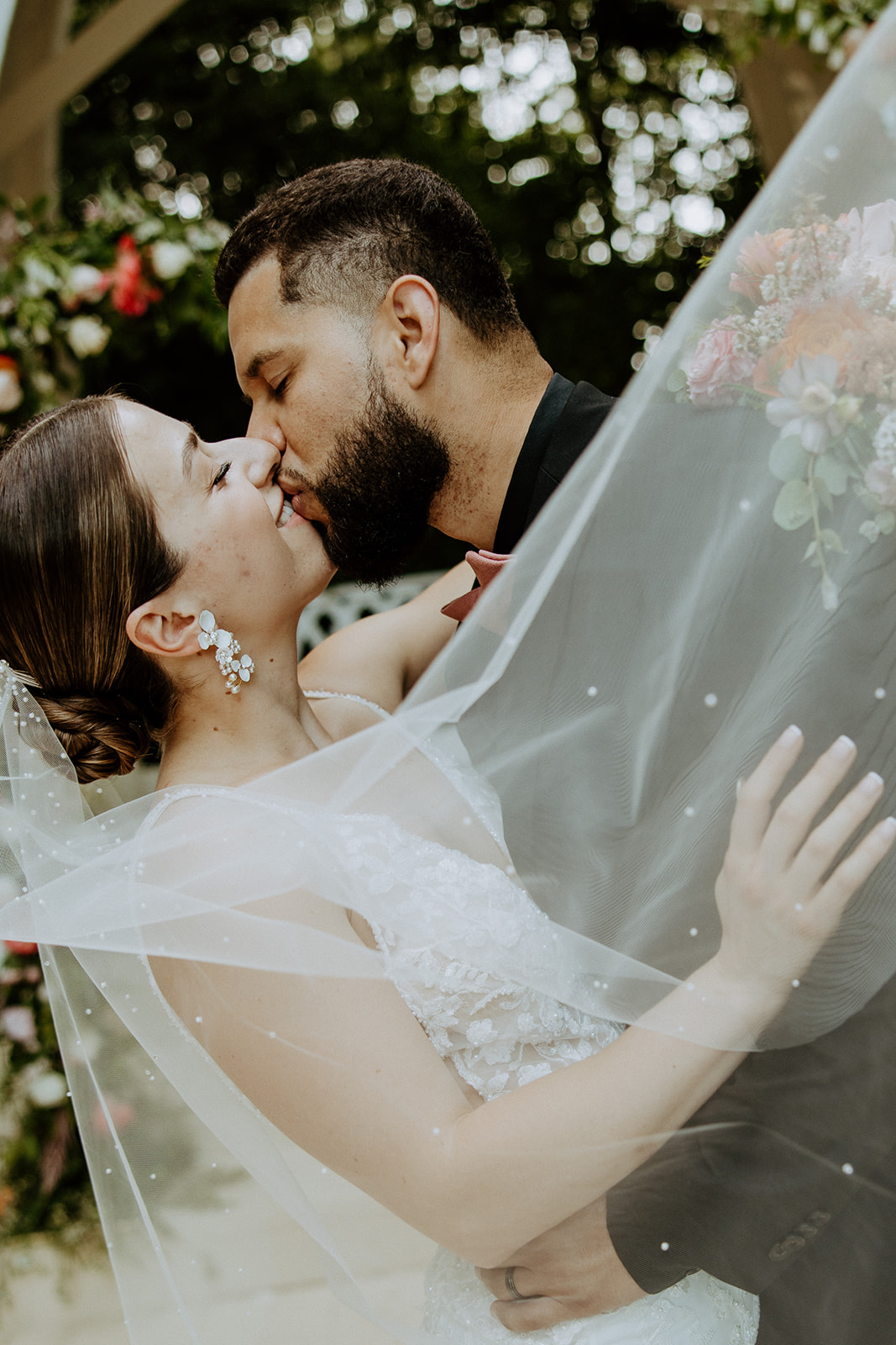 A bride and groom walk down an outdoor aisle holding hands, with empty chairs and an arch structure in the background at wildflower 301