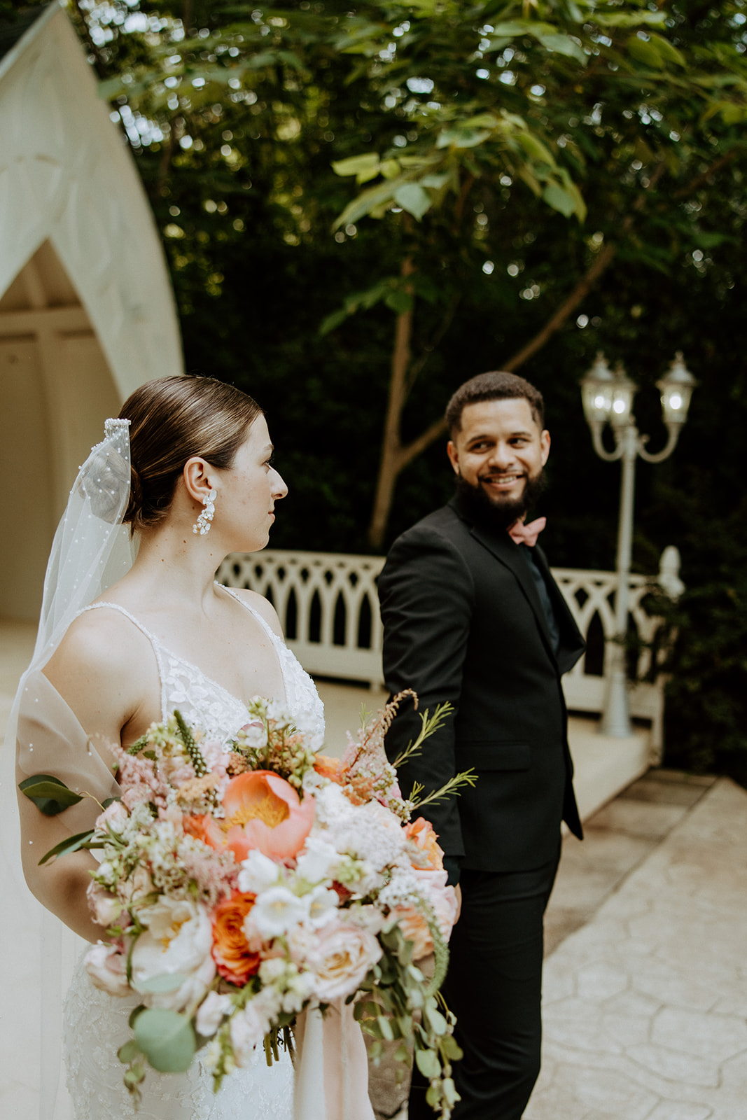 A bride and groom walk down an outdoor aisle holding hands, with empty chairs and an arch structure in the background at wildflower 301