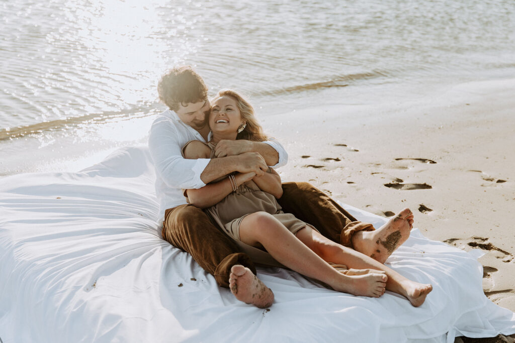 Two people lie on a mattress floating on a calm body of water, appearing relaxed and at ease on Tybee Island