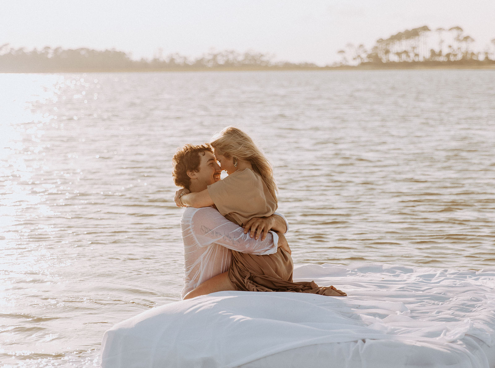 Two people lie on a mattress floating on a calm body of water, appearing relaxed and at ease on Tybee Island