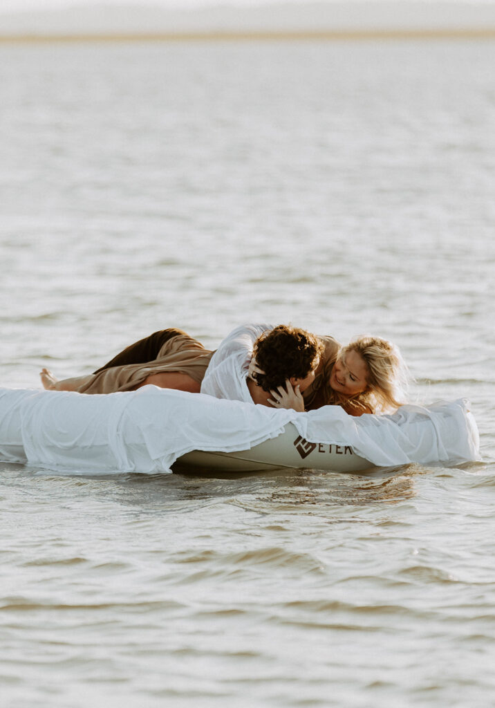 A couple lies together on a white inflatable raft floating on a body of water during daytime on Tybee Island 