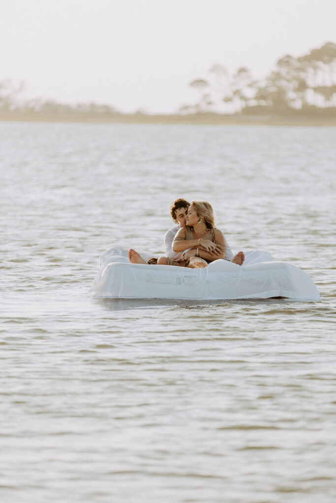 A couple lies together on a white inflatable raft floating on a body of water during daytime on Tybee Island 