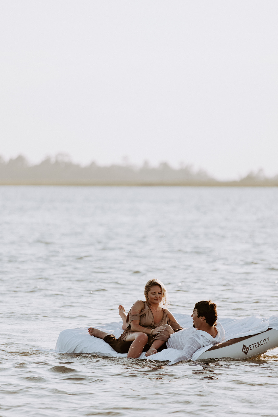 A couple lies together on a white inflatable raft floating on a body of water during daytime on Tybee Island 