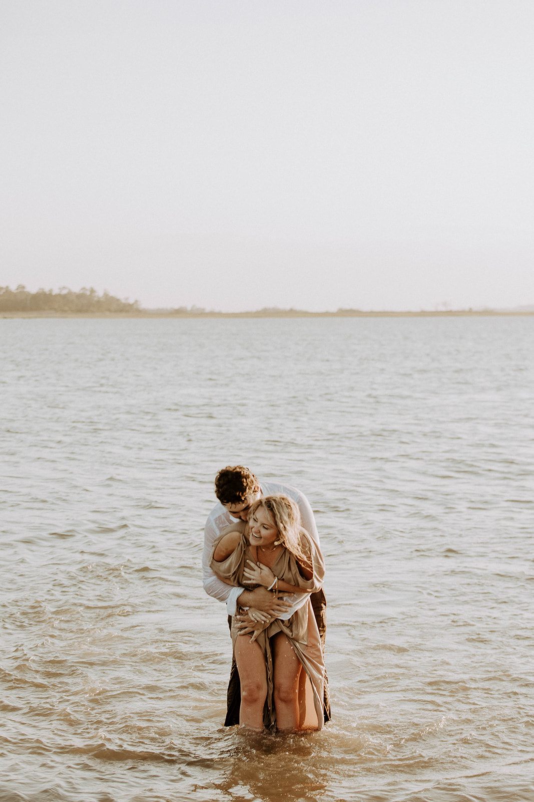 Couple having a fun and playful engagement photos session in the water