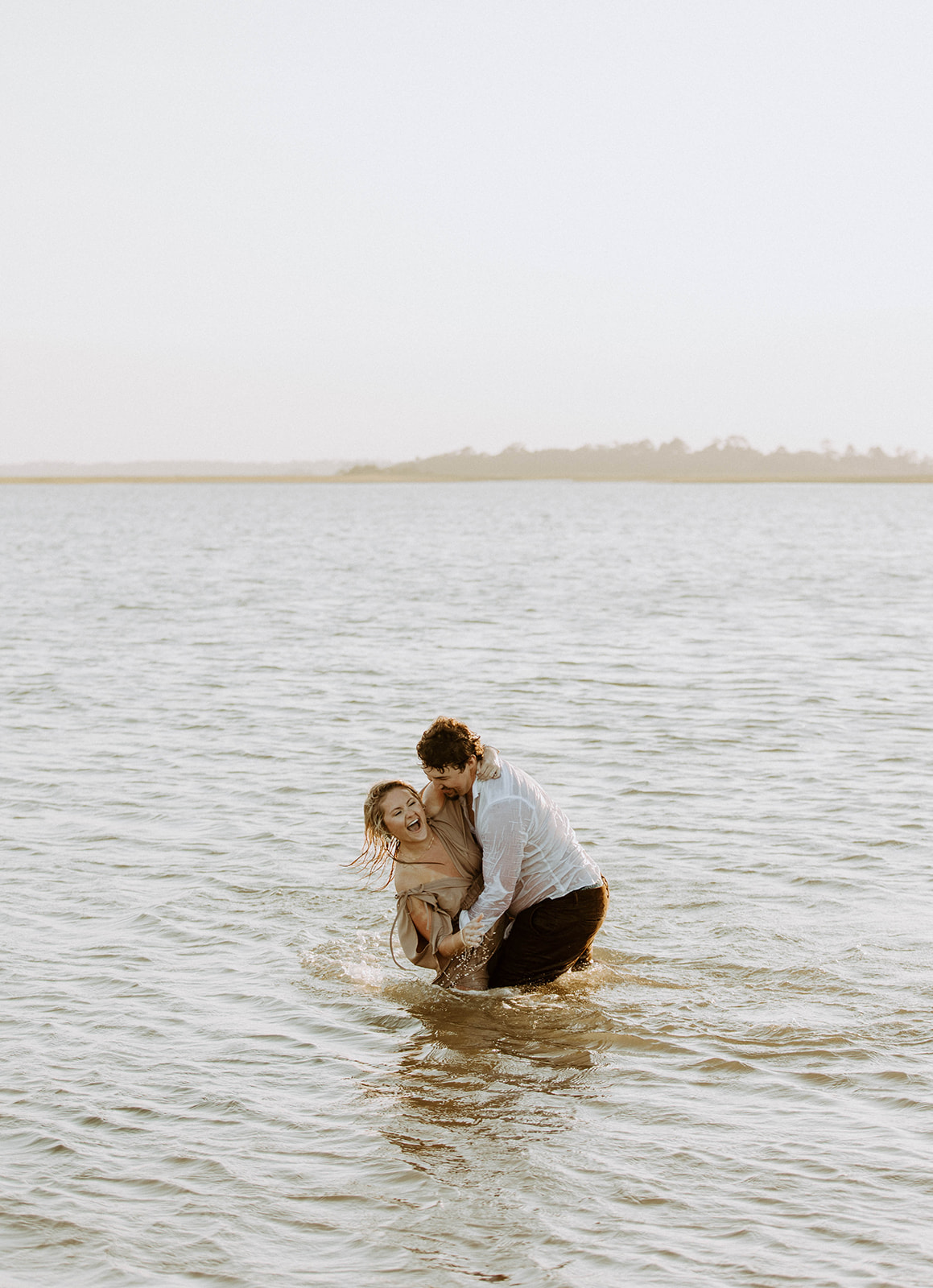 Couple having a fun and playful engagement photos session in the water