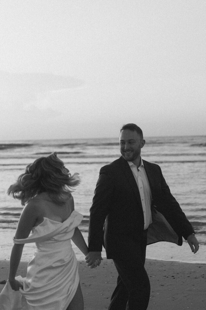 newlyweds running around the beach during their photoshoot