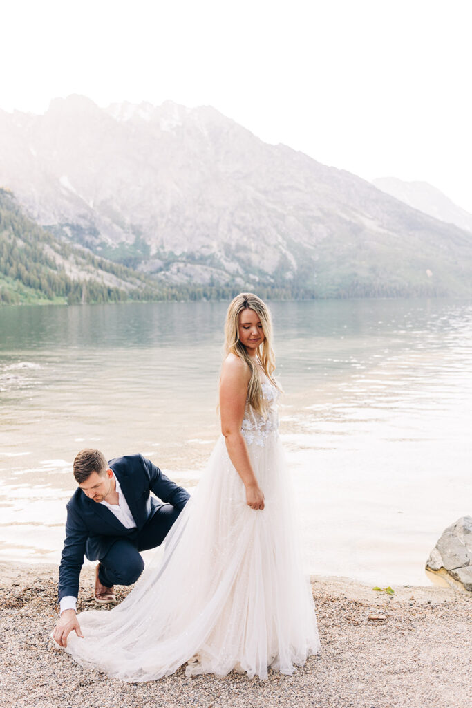 groom helping the bride with her wedding dress
