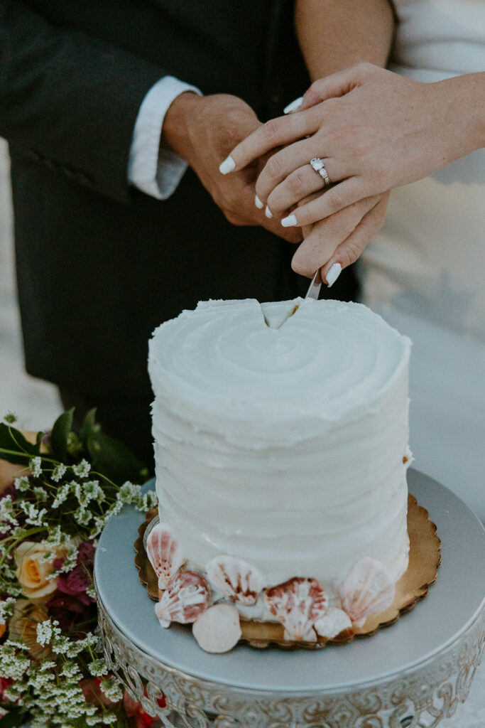 newlyweds cutting their wedding cake at the beach