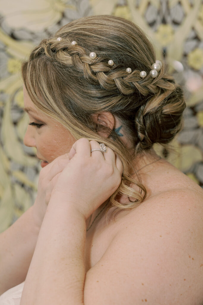 bride putting on her jewelry before the ceremony