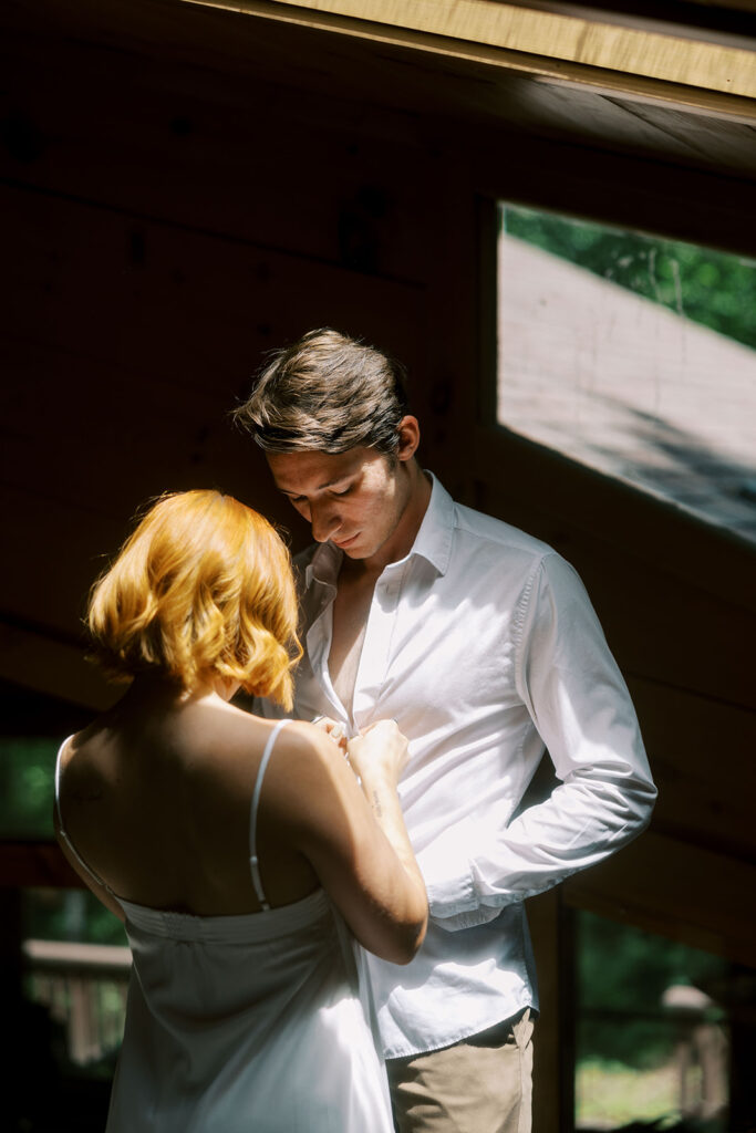 bride helping the groom with his shirt