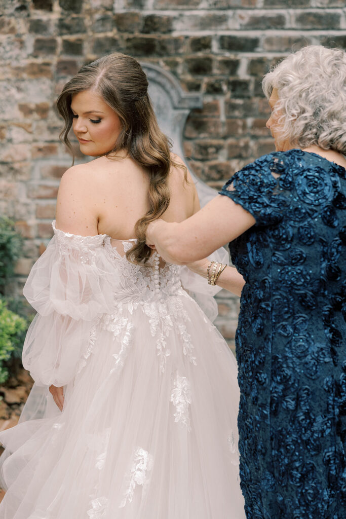 mother of the bride helping the bride with her wedding dress