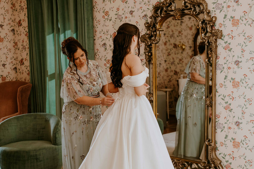 mother of the bride helping her with her wedding dress
