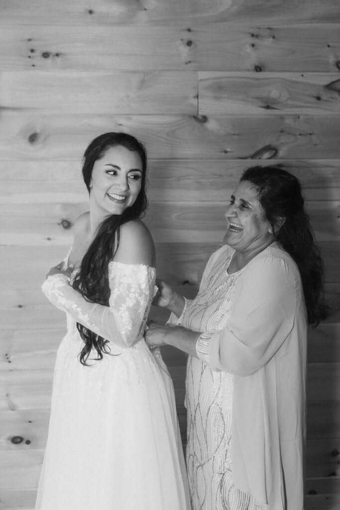 mother of the bride helping her with her wedding dress