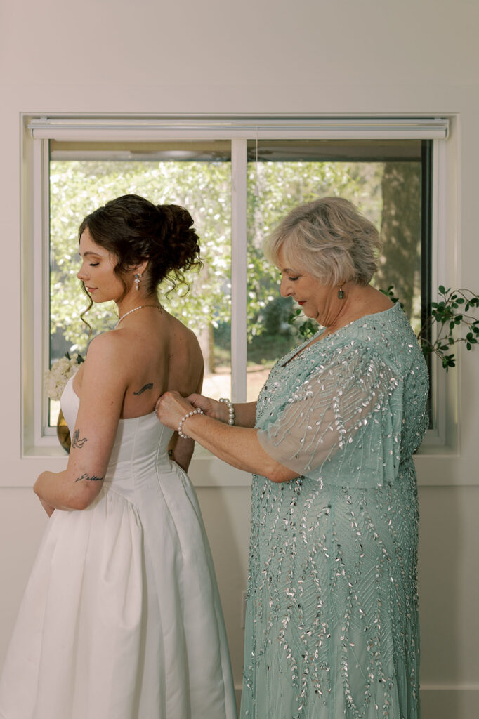 mother of the bride helping her with the wedding dress