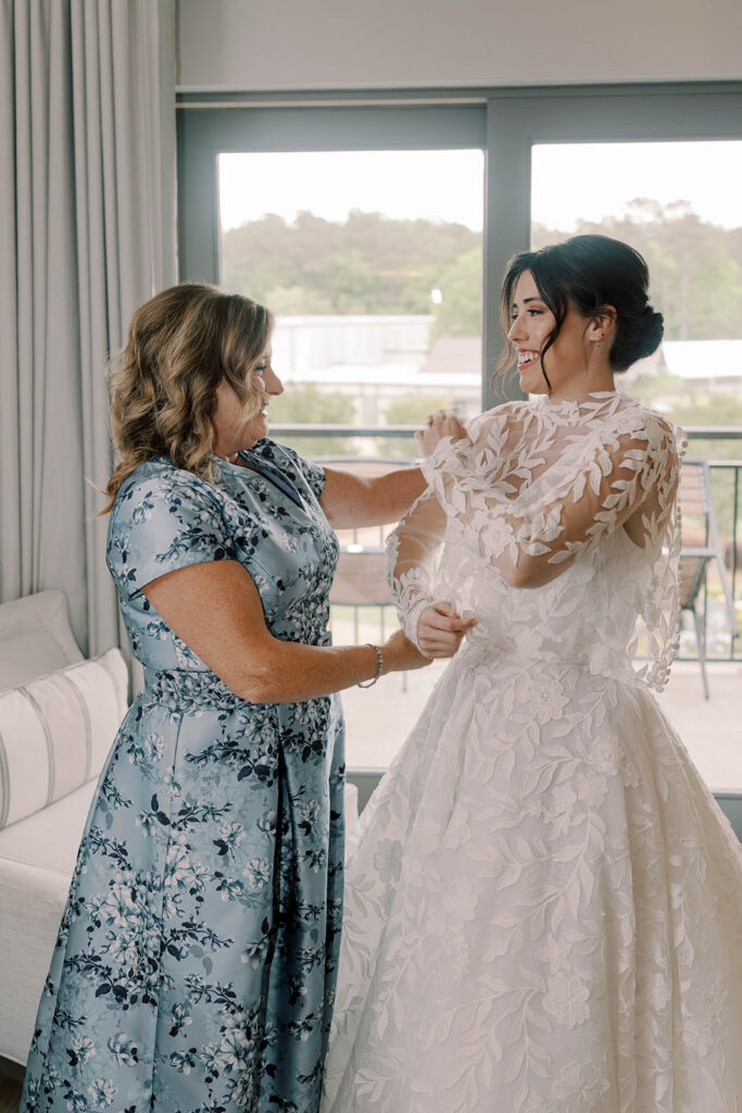 mother of the bride helping her with the wedding dress