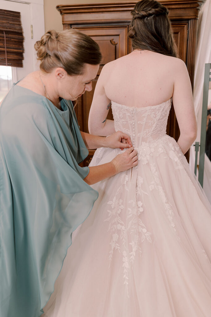 mother of the bride helping her with her wedding dress