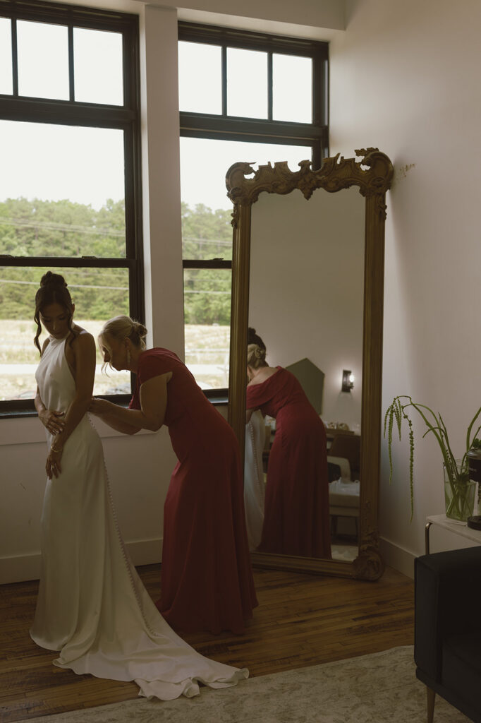 Mother of the bride helping her with the wedding dress
