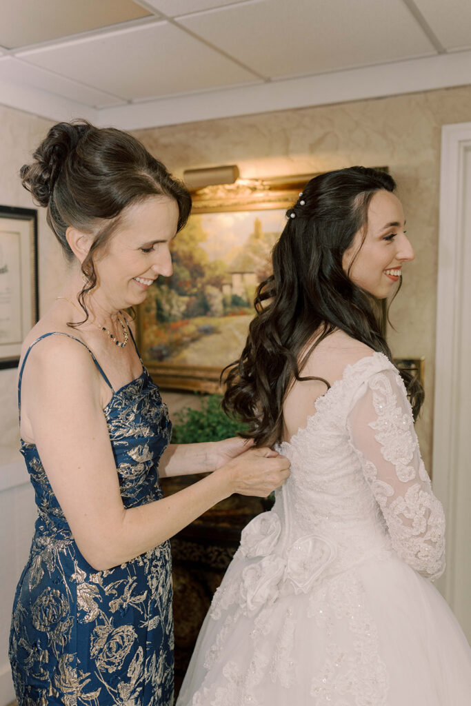 mother of the bride helping her with the wedding dress